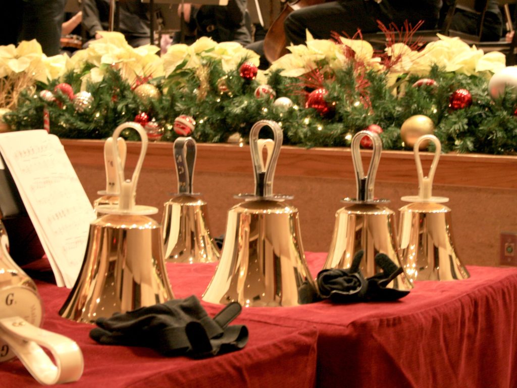 group of bells in church sanctuary with poinsettias in background